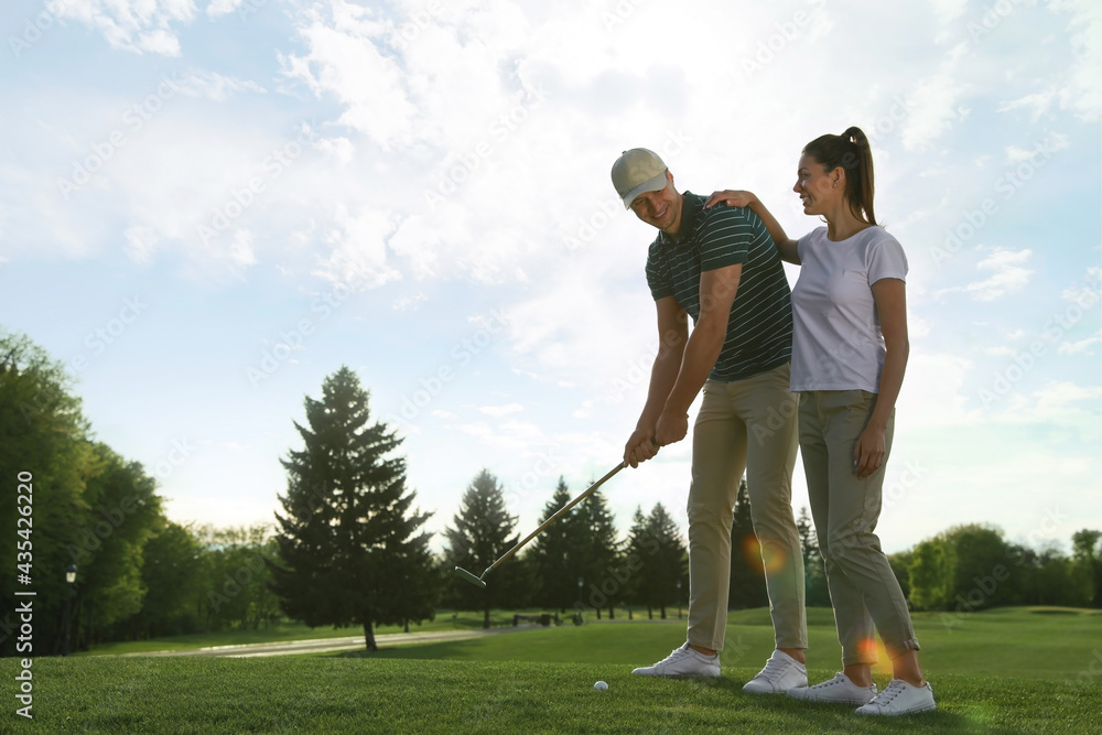 Happy couple playing golf on green course, space for text Happy couple playing golf on green course, space for text
