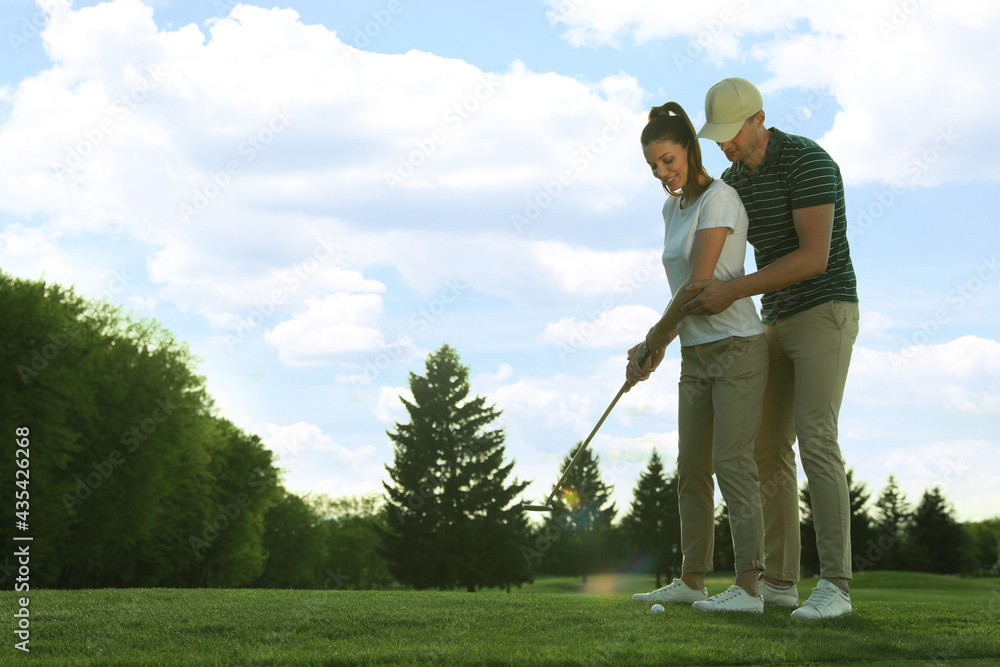 Man teaching his girlfriend to play golf on green course Man teaching his girlfriend to play golf on green course
