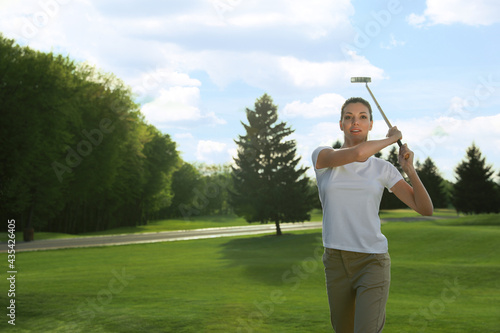 Beautiful woman playing golf on green course, space for text