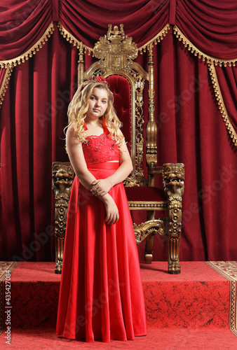 Blonde teenage girl in bright red dress standing in front of vin