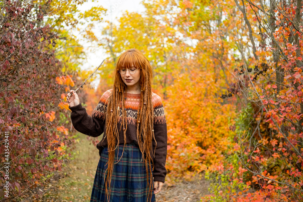 Young woman with red dreadlocks and wearing a sweater in the beautiful autumn forest Young woman with red dreadlocks and wearing a sweater in the beautiful autumn forest
