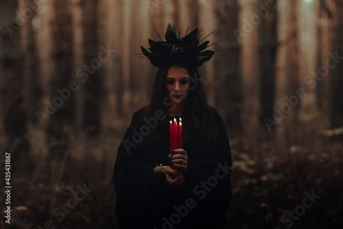 black terrible witch holds candles in her hands photo