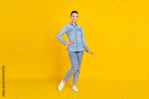 Full length photo of cute adorable young woman wear denim shirt smiling standing isolated yellow color background