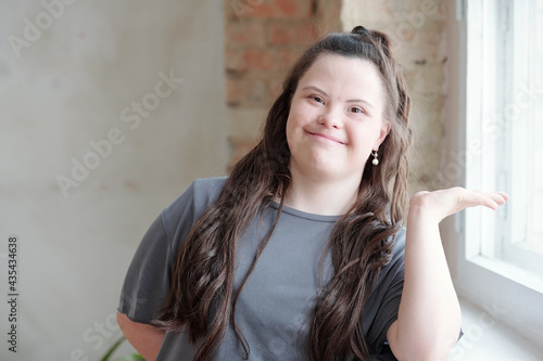 Friendly young brunette female with Down syndrome looking at you with smile photo