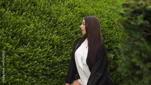 young attractive kardashian looking model dance going into a squad position looking in camera tempting cute posing surrounded by greenery in maze slow motion photo