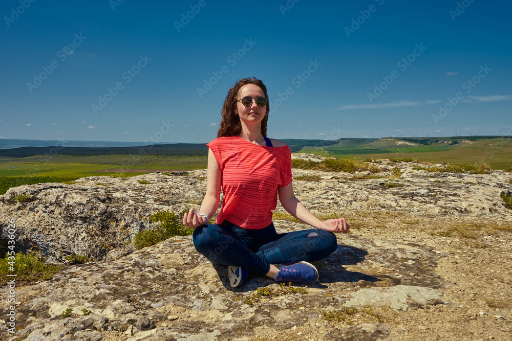 Girl meditating on the top of the mountain, doing yoga