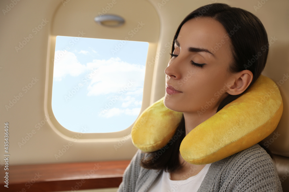 © New Africa - Young woman with travel pillow sleeping in airplane during flight © New Africa - Young woman with travel pillow sleeping in airplane during flight
