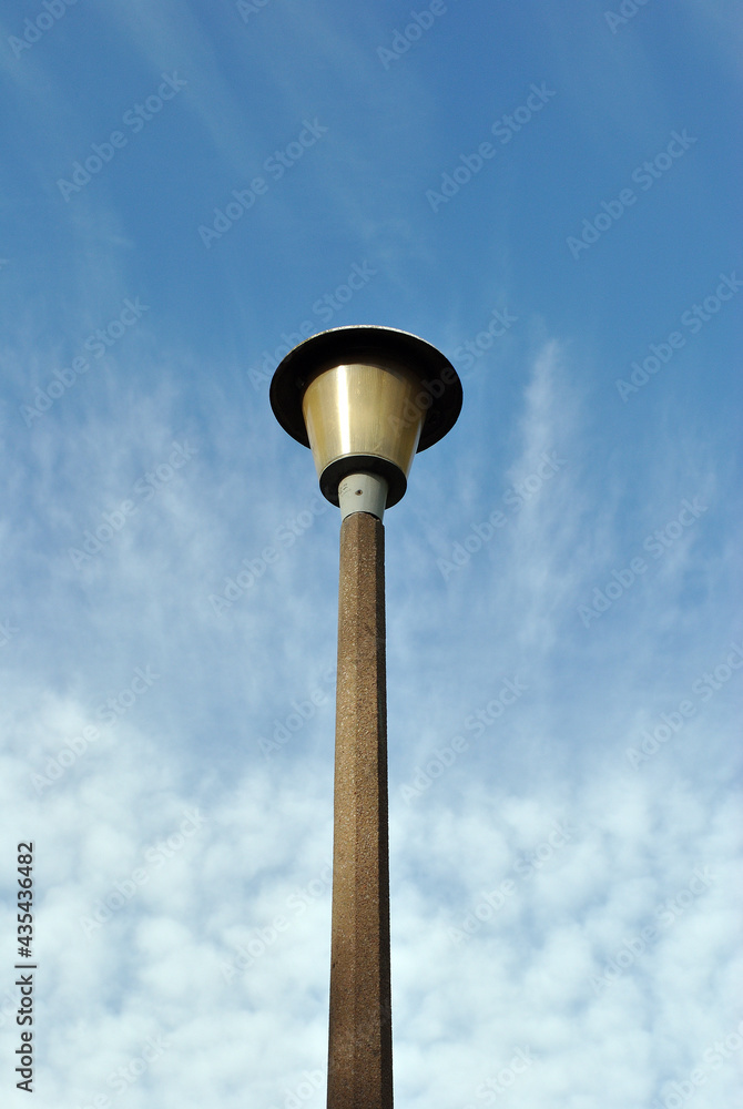 Modern Public Street Light on Single Concrete Post against Blue Sky 