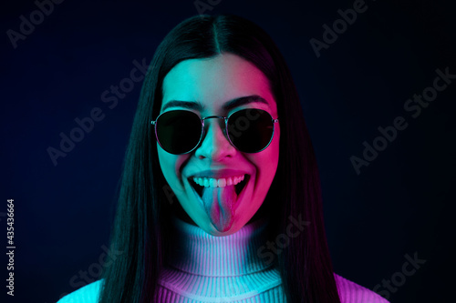 Photo of young cheerful girl happy positive smile fooling tongue-out brutal isolated over dark color background