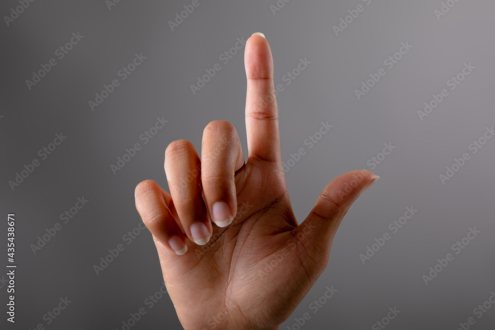 Close up of hand touching invisible screen against grey background