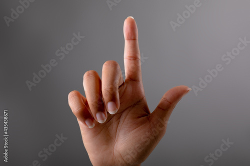 Close up of hand touching invisible screen against grey background