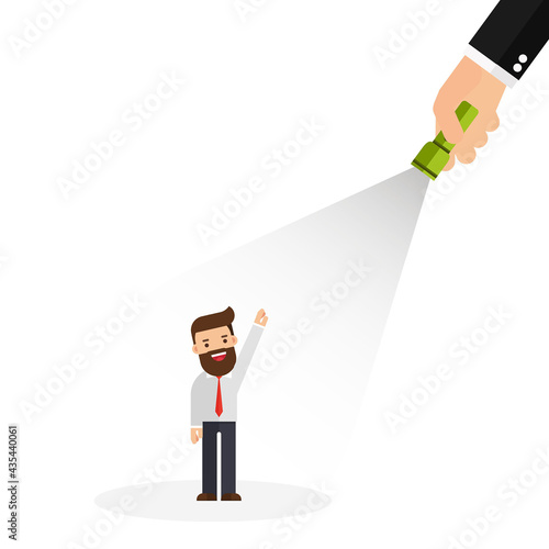 A hand holding a flashlight pointing at standing businessman