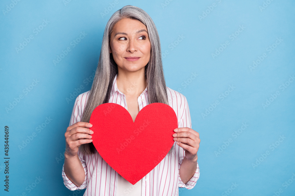 Portrait of attractive cheery woman holding big large heart looking aside copy space isolated over bright blue color background Portrait of attractive cheery woman holding big large heart looking aside copy space isolated over bright blue color background