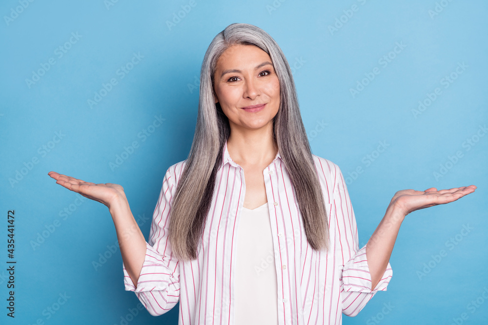 Portrait of attractive cheerful grey-haired woman holding on palms copy space pros cons isolated over bright blue color background Portrait of attractive cheerful grey-haired woman holding on palms copy space pros cons isolated over bright blue color background