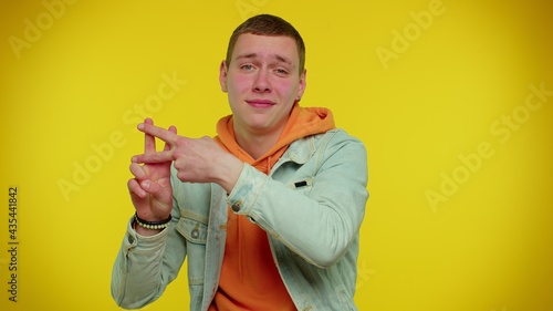 Hashtag. Cheerful teen boy showing hashtag symbol with hands, likes tagged message, popular viral content, sign to follow internet online trends. Young adult man on yellow indoor studio background