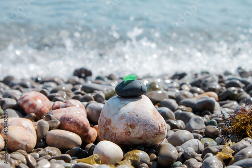 The pyramid is built on a pebble beach of sea pebbles with a matte smooth green glass at the top. Against the background of waves, water splashes and foam