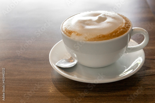 Hot coffee cappuccino latte spiral foam on dark wooden background, hot coffee with foam milk