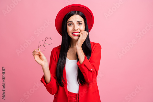 Photo portrait of scared woman biting nails taking of glasses isolated on pastel pink colored background