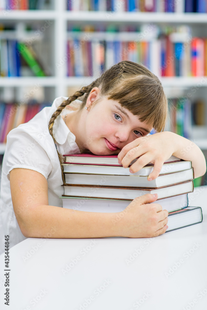 Happy young girl with syndrome down reads a book at library. Education for disabled children concept Happy young girl with syndrome down reads a book at library. Education for disabled children concept