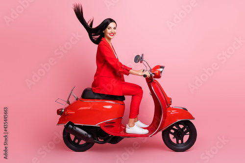 Full body profile side photo of young attractive woman happy positive smile driving red motorbike isolated over pink color background