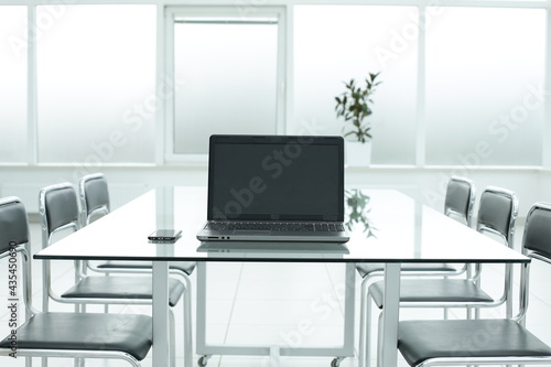 Grey laptop on glass table in office space © Qwenergy