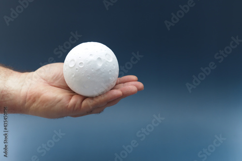 Man holds small figure of moon in one hand.