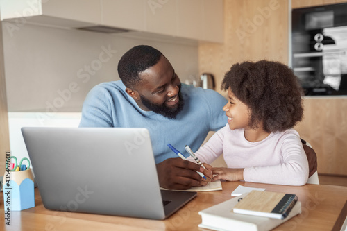 Happy young parent father help child daughter with distance learning from home