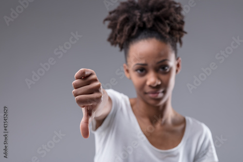 Unimpressed young woman giving a thumbs down gesture