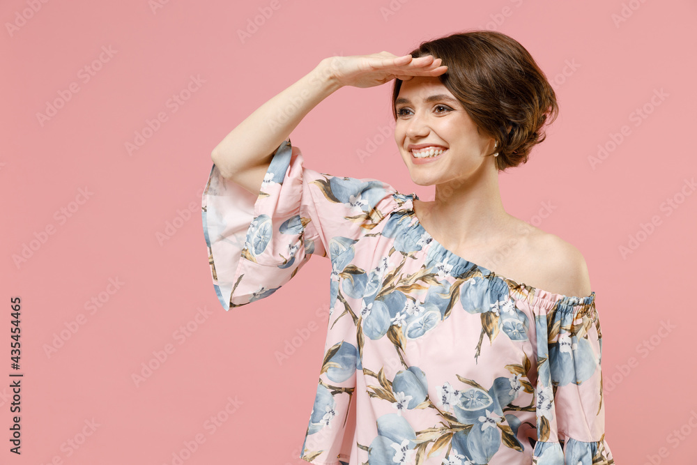 Young smiling happy caucasian woman 20s with short hairdo wear trendy blouse hold hand at forehead look far away distance isolated on pastel pink background studio portrait. People lifestyle concept. Young smiling happy caucasian woman 20s with short hairdo wear trendy blouse hold hand at forehead look far away distance isolated on pastel pink background studio portrait. People lifestyle concept.