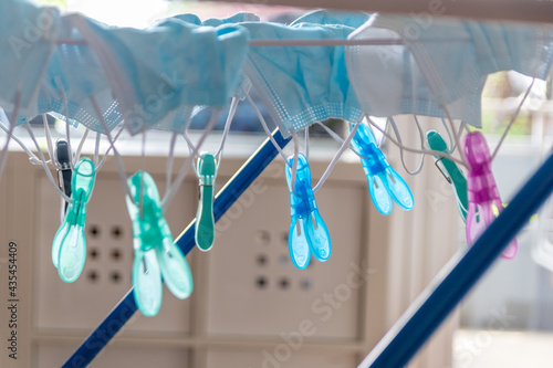 Washed surgical masks hanging on a clothes drying rack after disinfection with clothespins in pandemic times with covid-19 in quarantine to medical protection with face masks as essential item