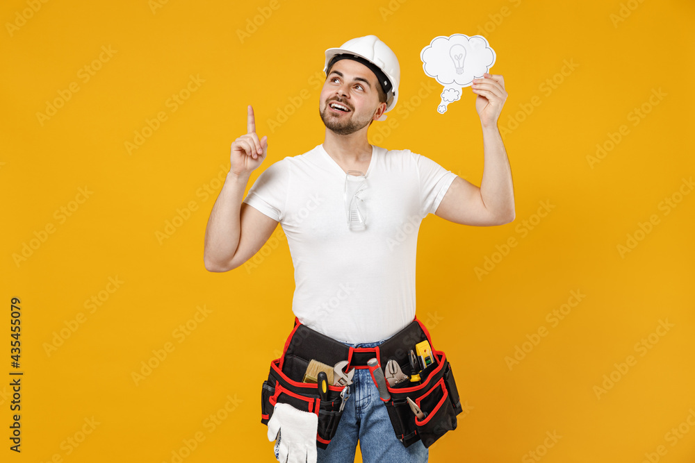 Young employee handyman man in protective helmet hardhat hold say cloud with lightbulb point finger up workspace isolated on yellow background Instrument renovation apartment room Repair home concept Young employee handyman man in protective helmet hardhat hold say cloud with lightbulb point finger up workspace isolated on yellow background Instrument renovation apartment room Repair home concept