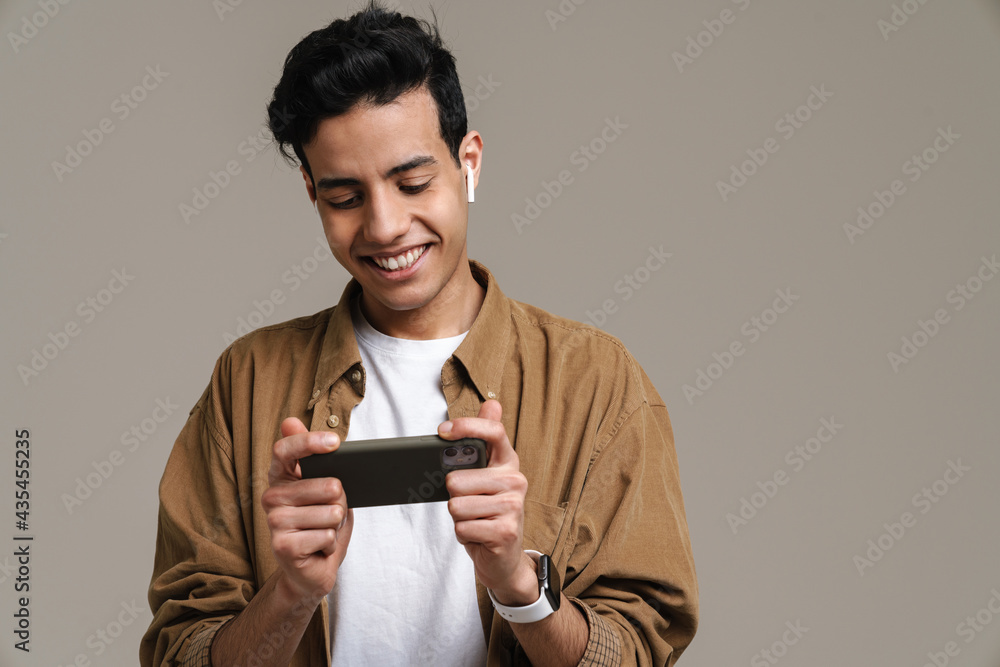 Brunette hispanic man smiling while using cellphone and earphones Brunette hispanic man smiling while using cellphone and earphones