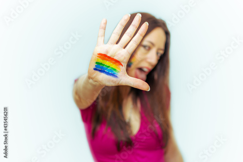Young woman with LGTBIQ+ flag painted on hand screaming.selective focus on hand and white background.