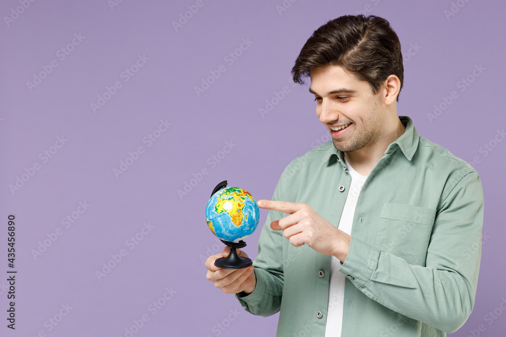Young fun smiling excited happy caucasian man 20s wearing casual mint shirt white t-shirt spin touch Earth world globe isolated on purple violet background studio portrait People lifestyle concept Young fun smiling excited happy caucasian man 20s wearing casual mint shirt white t-shirt spin touch Earth world globe isolated on purple violet background studio portrait People lifestyle concept