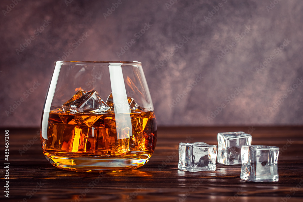 scar coin Commander A glass of whiskey close up. Brandy with ice on a brown wooden table. Cognac,  bourbon. Strong alcoholic drink. Transparent yellow alcoholic beverage.  Stock Photo | Adobe Stock