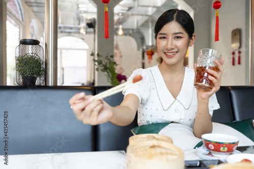 Fotografie young woman holding chopsticks and eating Chinese foods