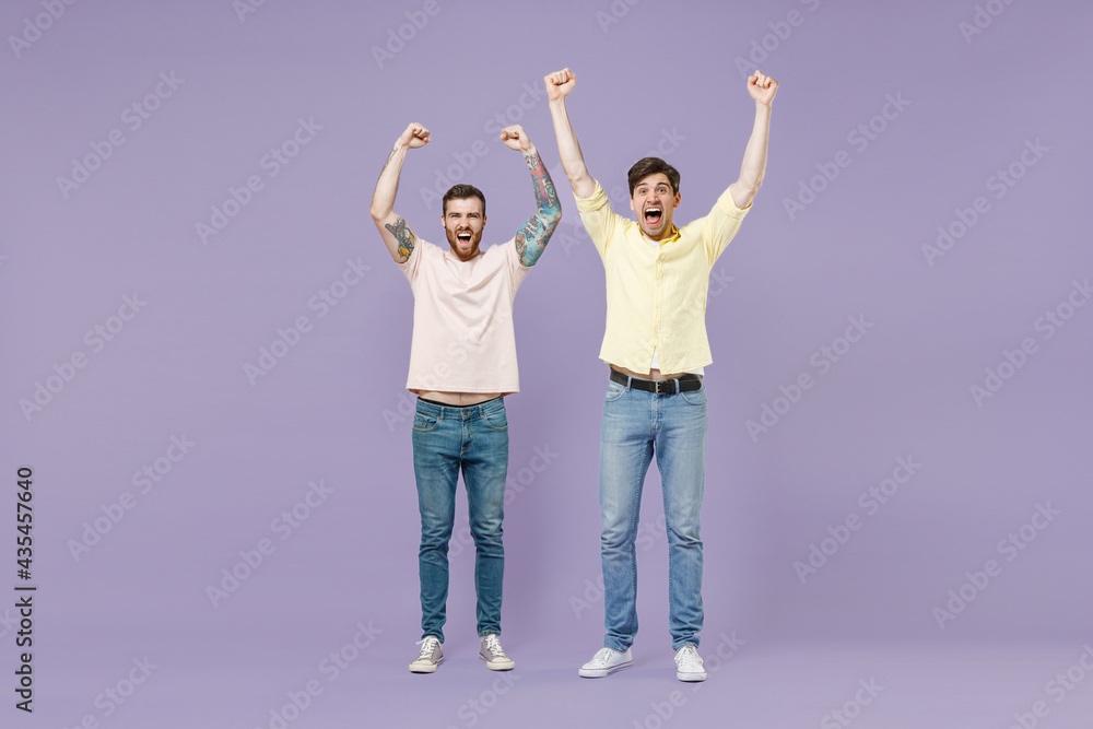 Full length overjoyed excited two young happy men friends together walk in casual t-shirt walk do winner gesture clench fist isolated on purple background studio People friendship lifestyle concept Full length overjoyed excited two young happy men friends together walk in casual t-shirt walk do winner gesture clench fist isolated on purple background studio People friendship lifestyle concept
