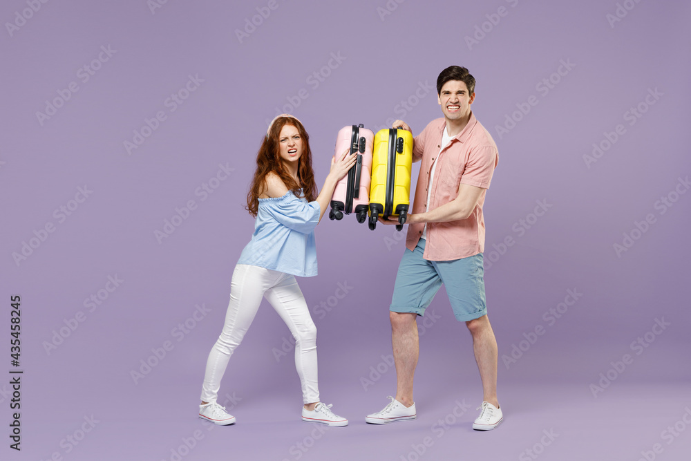 Naklejka premium Full length two fun traveler tourist woman man couple in shirt holding suitcase fooling around isolated on purple background. Passenger travel abroad on weekends getaway. Air flight journey concept.