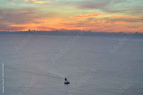Fishing boat returning to shore in early morning with dawn of beautiful sunlight.