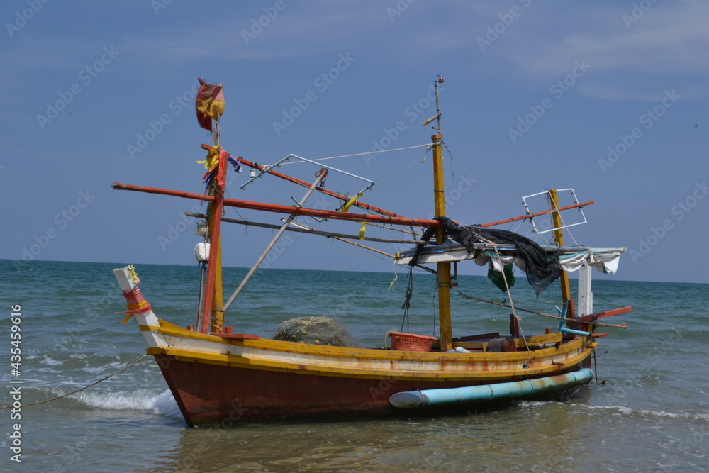 Small fishing boat on shallow beach with blue skay on background Small fishing boat on shallow beach with blue skay on background