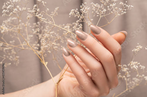 Fototapeta Female hand with glitter beige nail design