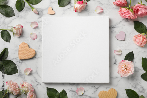Flat lay composition with blank canvas and beautiful roses on white marble background. Mockup for design