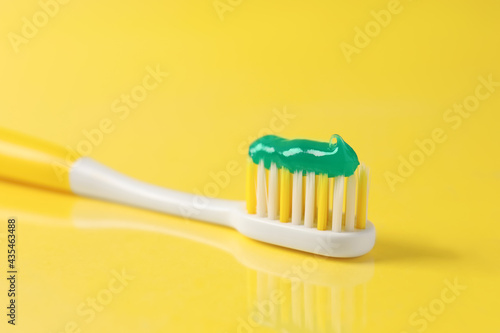 Brush with toothpaste on yellow background  closeup