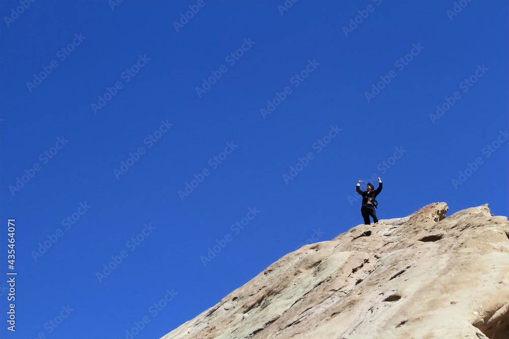 A young Japanese businessman on the huge rock who is happy to work well