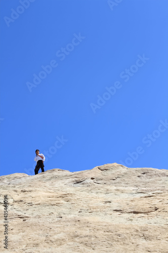 Young businessman standing on a huge rock 