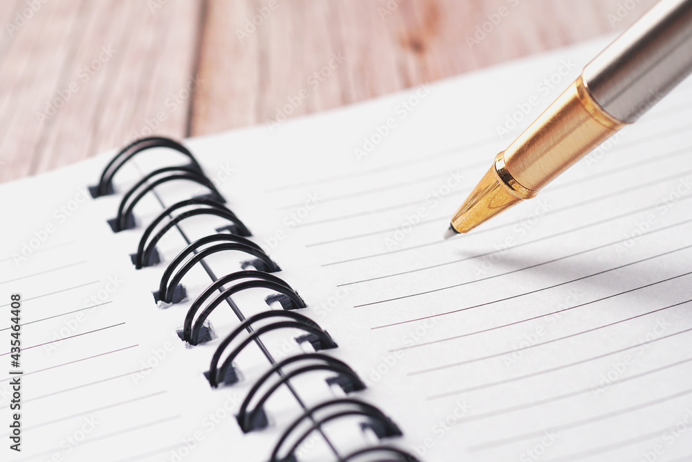 Golden pen and white paper notebook with lines Golden pen and white paper notebook with lines