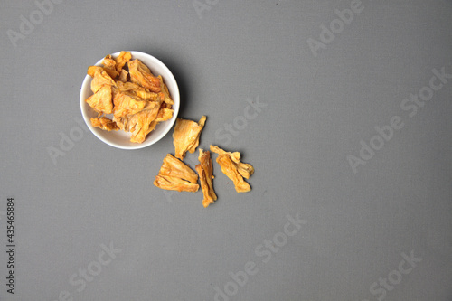 Healthy eating concept - a bowl of dried pineapple isolated on gray background flat lay