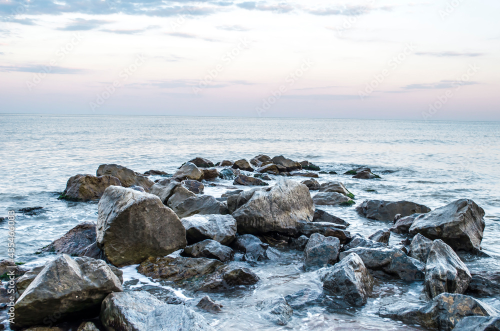 Sea stones boulders sandy shore. Natural landscape.