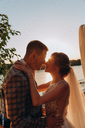 Evening walk of the newlyweds by the lake. Portrait of the bride and groom. Photoshoot at sunset.