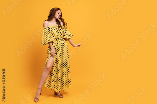 Red-head woman in yellow dress posing in studio. Summer mood. Full lenght.